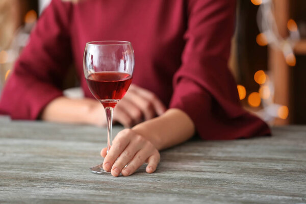 Woman with glass of wine at wooden table