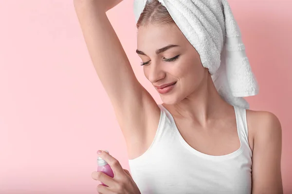 Beautiful young woman with deodorant on color background