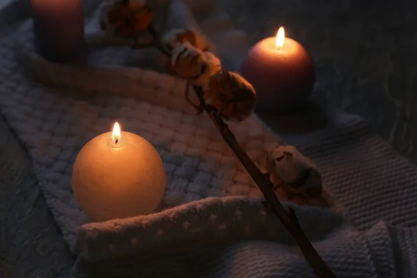 Burning candles and cotton flowers on table in darkness