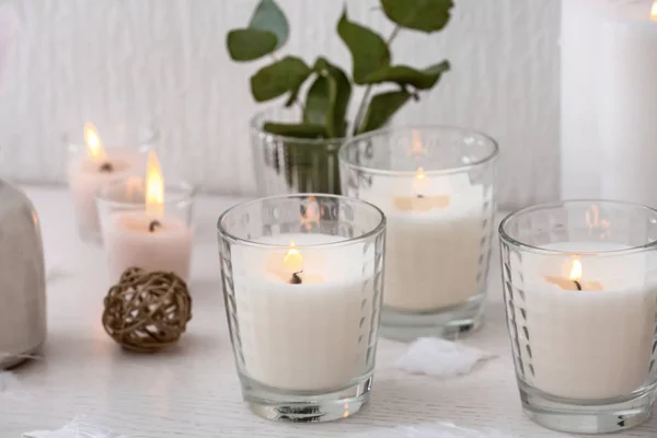 Beautiful burning candles on white wooden table