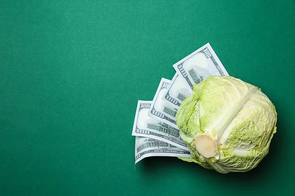Fresh cabbage with dollars on color background, top view