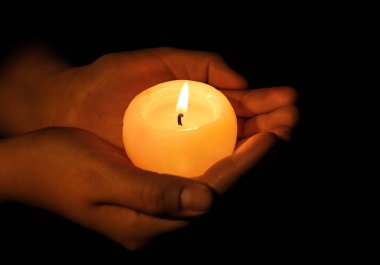 Koyu arka plan üzerinde yanan mum tutan kadın