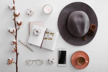 Cep telefonu, şapka, beyaz arka plan üzerinde yanan mum ve açık defter ile düz yatıyordu kompozisyon