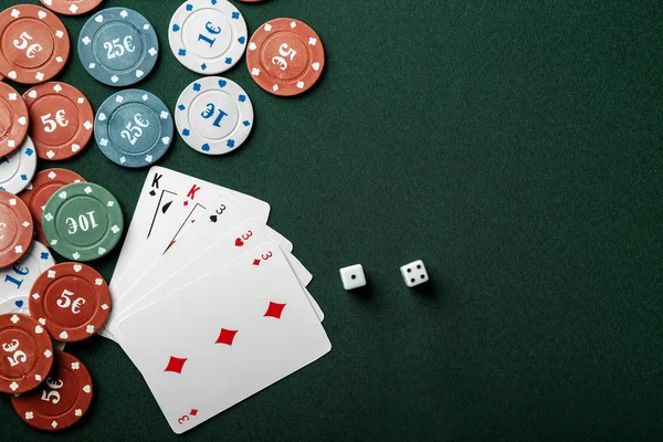 Chips with cards and dices for poker game on green table in casino