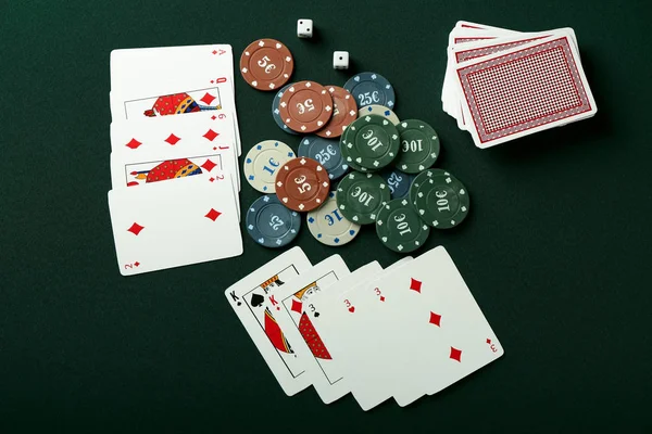 Chips with cards and dices for poker game on green table in casino