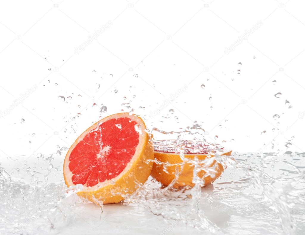 Fresh grapefruit with splashing water on white background