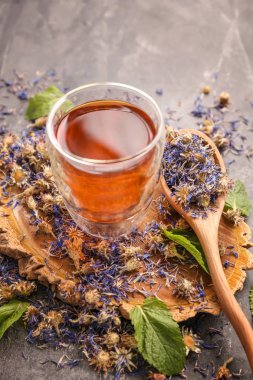 Bardak sıcak çay ve gri masaya kurutulmuş çiçek