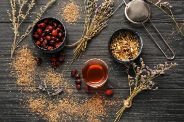 Kurutulmuş çiçek ve rose hips ahşap masa üzerinde sıcak çay bardak