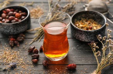 Kurutulmuş çiçek ve rose hips ahşap masa üzerinde sıcak çay bardak