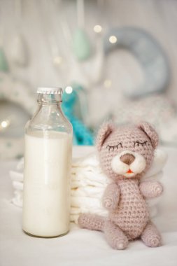 Şişe süt ayı oyuncak ve çocuk bezi yatakta yığını ile