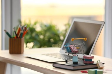 Kağıt poşet ve ahşap masa üstünde laptop küçük arabası. Online alışveriş