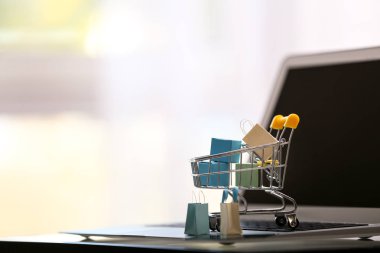 Kağıt poşet ve cam masa üstünde laptop küçük arabası. Online alışveriş