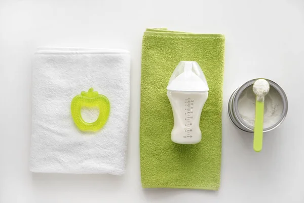 Feeding bottle of baby formula with powder and towels on white background