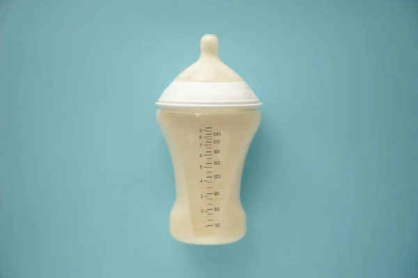 Feeding bottle of baby formula on color background