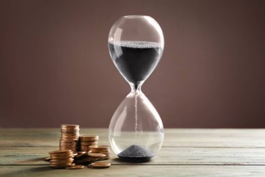 Siyah kum ve renk ahşap masa üzerinde para ile kristal kum saati. Zaman para demektir