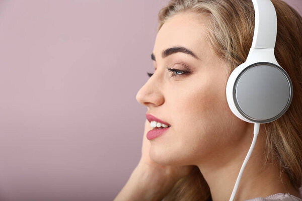 Beautiful young woman listening to music on color background