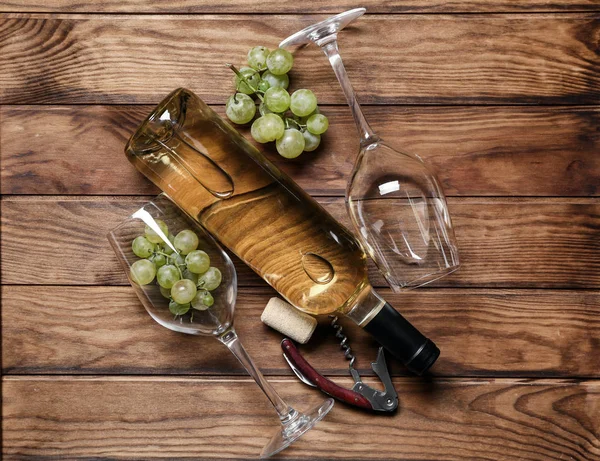 ガラスと木製のテーブルに栓抜きと白ワインのボトル — ストック写真