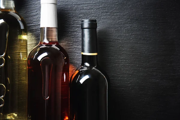 Bottles with different kinds of wine on dark background