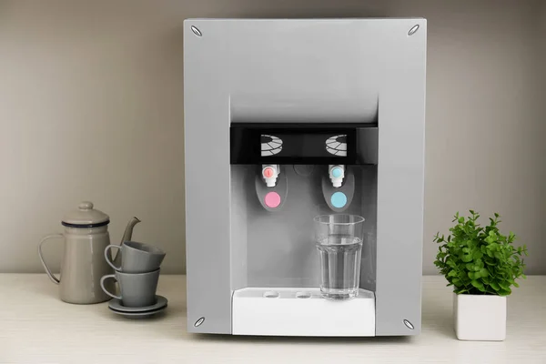 Modern water cooler with glass on kitchen table