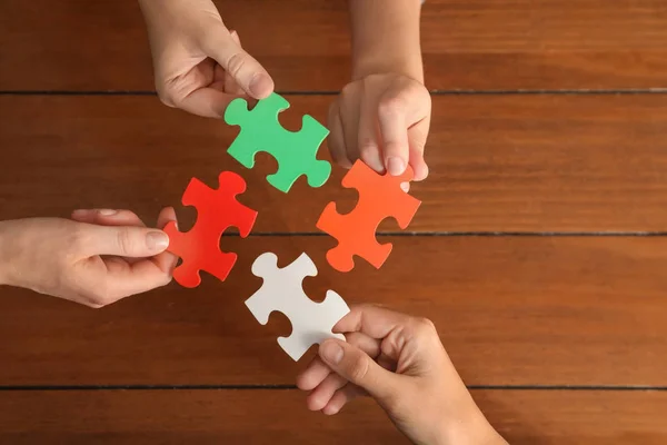 Les Gens Assemblant Puzzle Couleur Sur Fond Bois — Photo