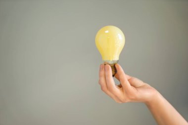 Ampul gri arka plan üzerinde tutan kadın