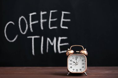 Koyu arka plan karşı ahşap masa çalar saat