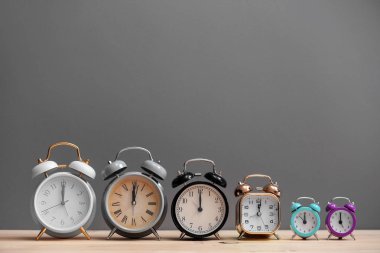 Ahşap masa gri arka plan üzerinde farklı korku masa saati