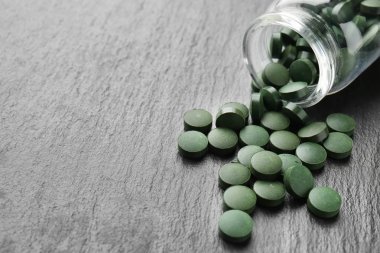 Spirulina tablet koyu arka plan üzerinde şişesiyle