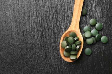 Spirulina tablet koyu arka plan üzerine kaşıkla