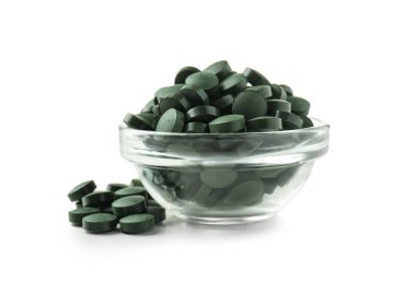 Beyaz arka plan üzerinde spirulina tablet ile cam kase