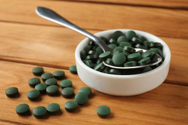 Kase ve ahşap masa spirulina tablet kaşıkla