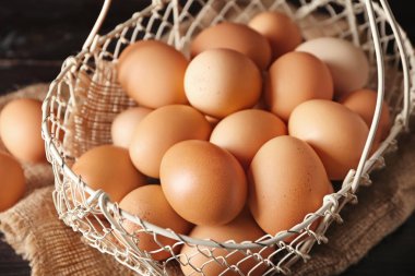 Çiğ tavuk yumurtası ahşap masa üstünde sepetle
