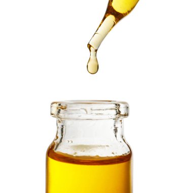 Beyaz arka plan üzerinde cam şişe içine pipet yağdan damlayan