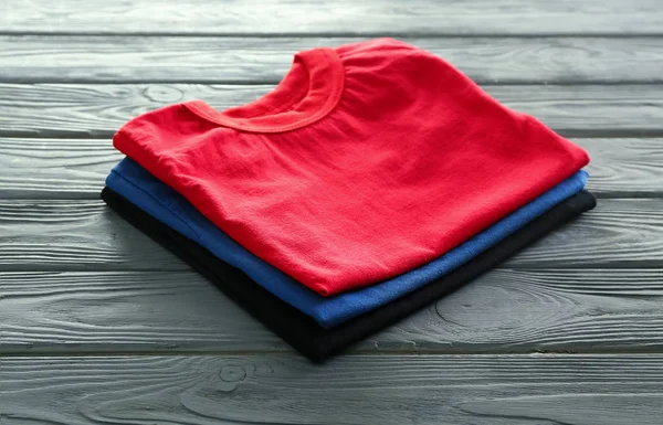 Στοίβα Από Πολύχρωμα Μπλουζάκια Φόντο Ξύλινη — Φωτογραφία Αρχείου