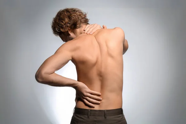 Young Man Suffering Back Pain Light Background — Stock Photo, Image