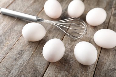 Ahşap arka plan üzerinde çırpma teli ile çiğ tavuk yumurta