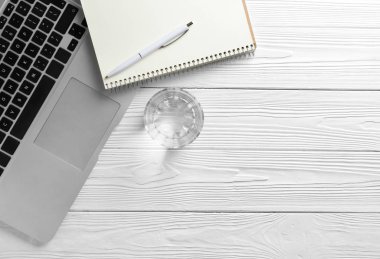 Dizüstü bilgisayar ve beyaz ahşap masa üstünde defter taze su