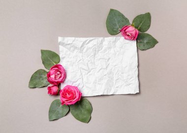Güzel pembe gül ve gri arka plan üzerinde buruşuk kağıt kartı kompozisyonu