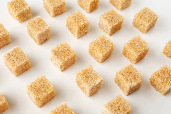 Brown cane sugar cubes on white background