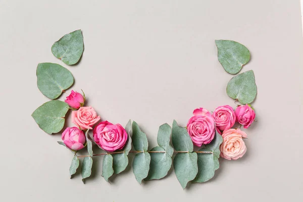 Composition with beautiful pink roses and eucalyptus leaves on grey background