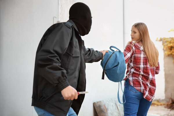 Вор-мужчина крадет сумку у молодой женщины на улице
