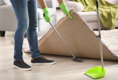 Genç adam dairesini temizliyor.