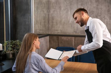 Genç garson kadın bir menü restoranda gösterilen.