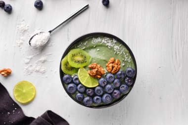Beyaz ahşap masa üzerinde lezzetli spirulina güler yüzlü ile kase