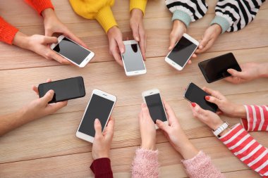 Cep telefonları ahşap masa kullanan gençlerin. Bağımlılık kavramı