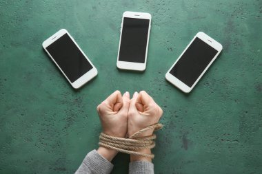 Kadın bağlı elleriniz ve renk arka plan üstünde hareket eden telefon. Bağımlılık kavramı