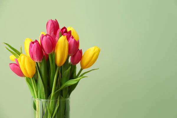 Vase with beautiful tulips on color background