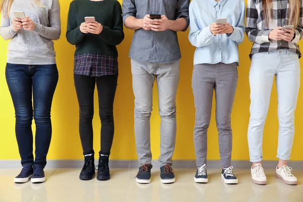 Молодые Люди Используют Мобильные Телефоны Возле Цветной Стены Концепция Зависимости — стоковое фото