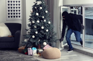 Male thief entering house through window clipart