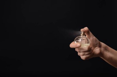 Kadın koyu arka plan üzerinde parfüm şişe